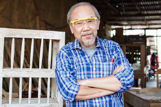 Portrait of Asian male carpenter with arms crossed at carpentry workshop