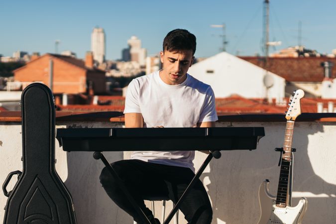 Front view of a man playing music keyboard on a rooftop
