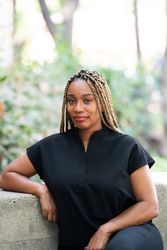 Portrait of heath care worker wearing black scrubs sitting on stone bench