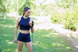 Female working out arms in park with resistance band