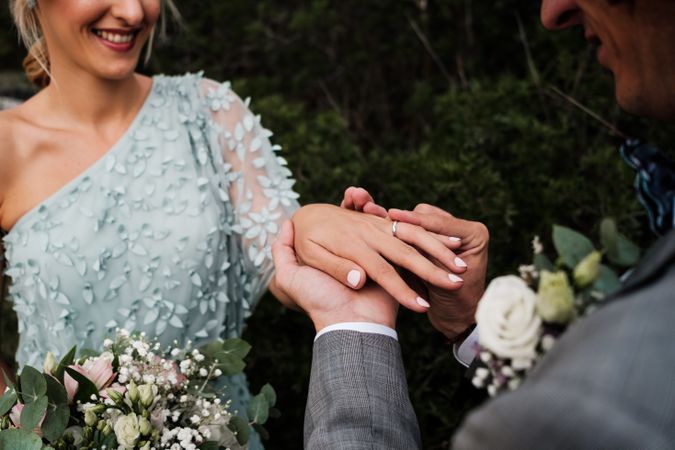 Cheerful newly wedded couple exchanging rings