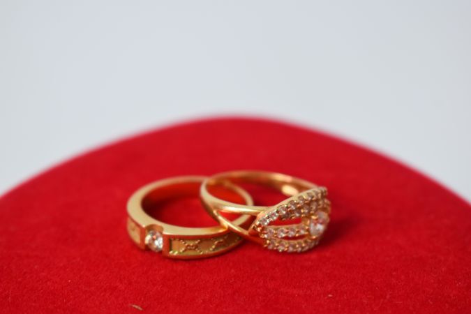 Two diamond gold wedding rings on red fabric with copy space