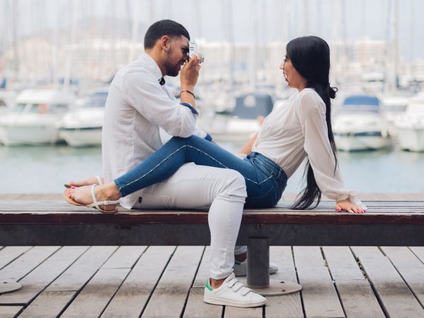 Man taking photo and sitting with man on bench