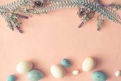 Creative layout made with spring flowers leaves and Easter eggs on pastel pink background
