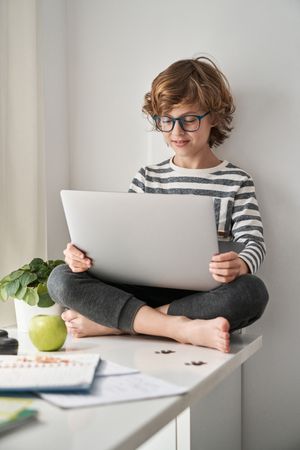 Focused boy doing homework on laptop at home