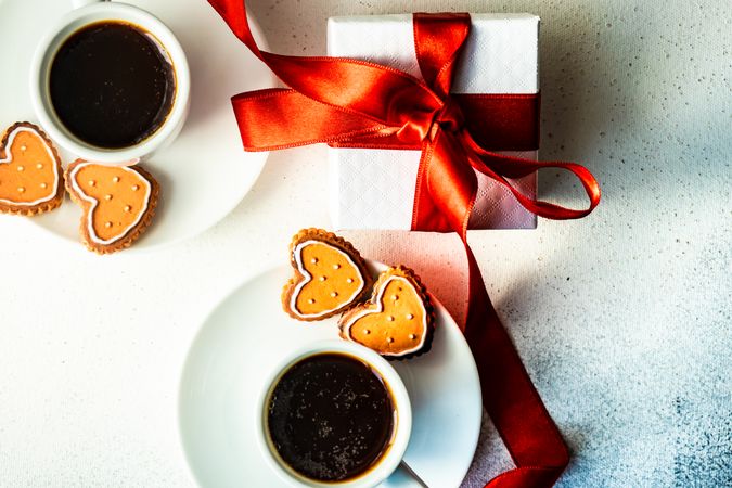 Top view of two coffees with iced cookies, gift and heart candles