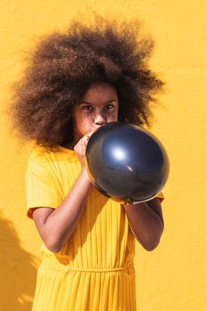 Black girl blowing party balloon