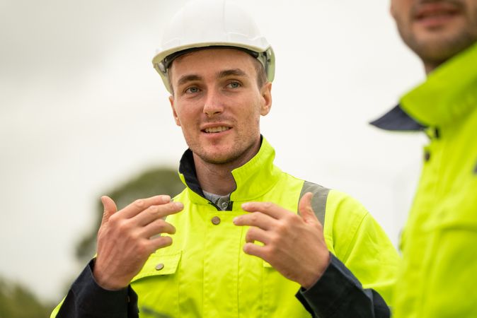 Engineer worker in protective uniform talking with colleagues at construction site