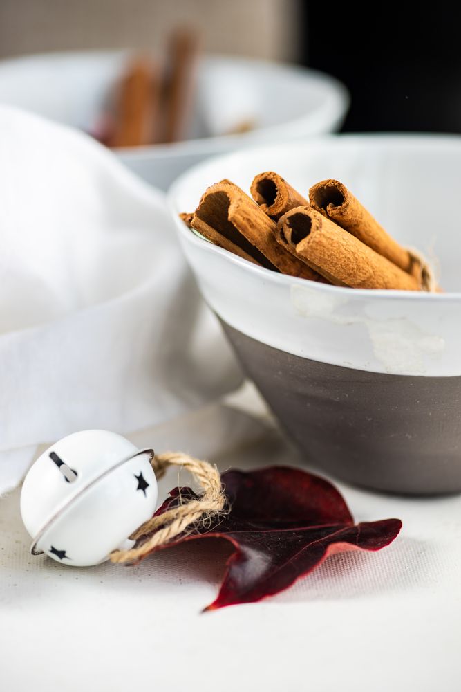 Winter table setting of cinnamon sticks in bowls with bell and leaves