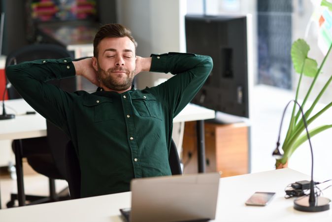 Young man relaxing between studying with laptop computer in modern office