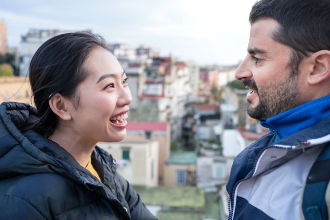 Positive multiethnic resting couple talking while walking at city street