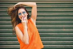 Carefree woman with hand to her mouth outside