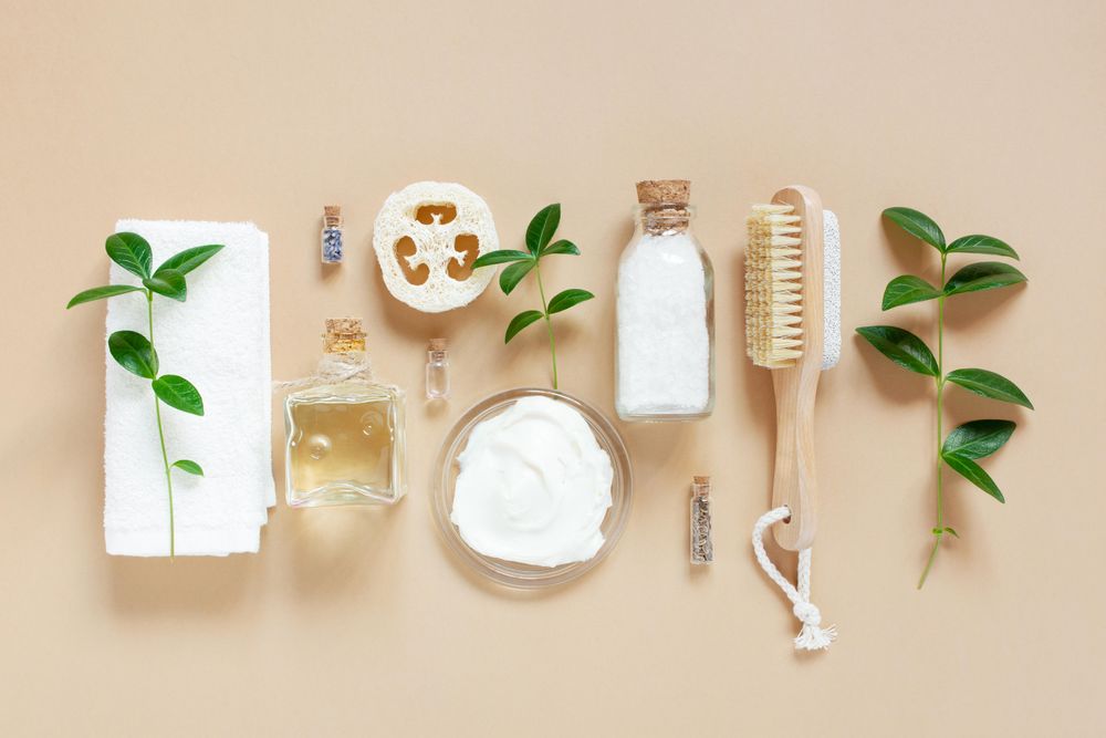 Relaxing bath salts and oils, loofah and brushes on beige with green branches