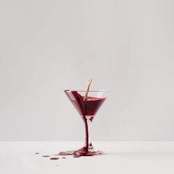 Doll hand drowning in martini glass full of blood