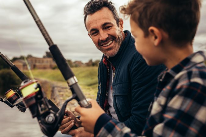 Close up of father and son fishing together near a lake