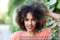 Portrait of funny Black woman with afro hairstyle in front of wall with vines 0vZxx0