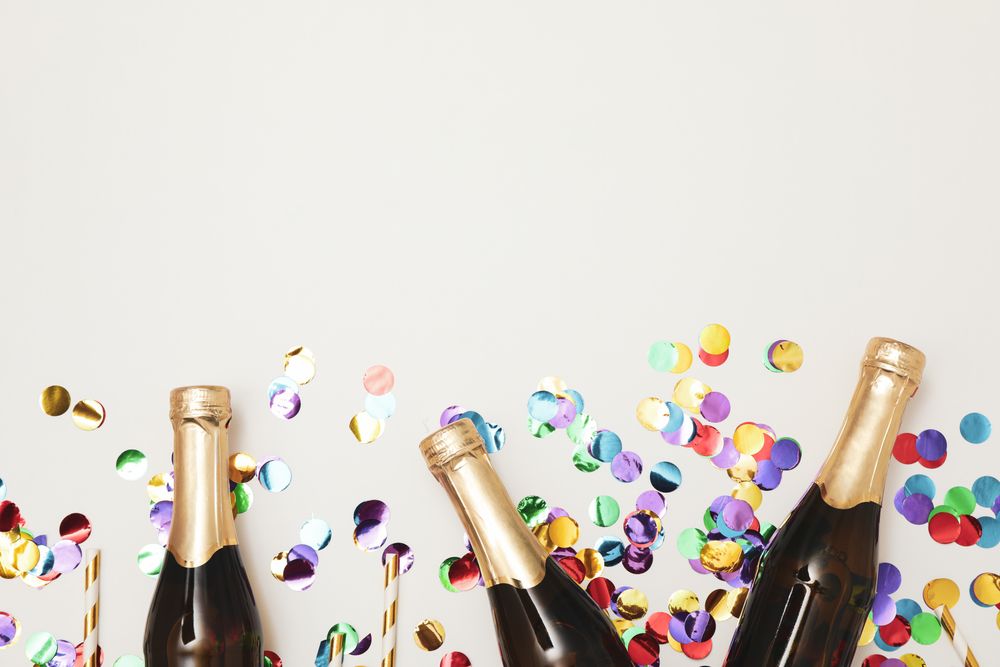 Composition with mini champagne bottles and glitter on light background, copy space