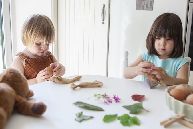 Girl and boy sitting in kitchen decorating eggs