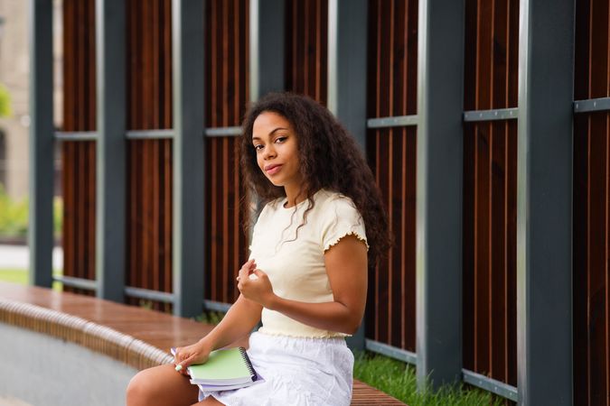 Black female student resting on bench outside