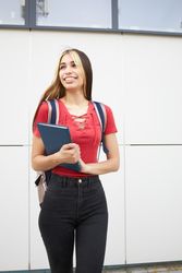 Portrait of smiling female student with backpack and notebook