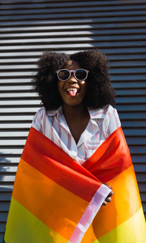 Black female posing happily with the LGBT flag