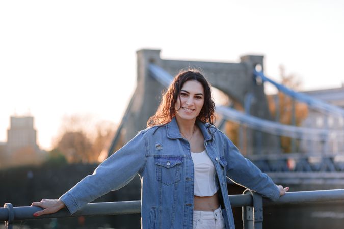 Woman standing by bridge along the waterfront at sunset