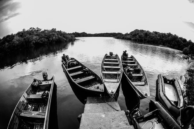 Five canoes parked near staircase in grayscale