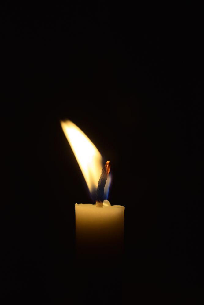 Side view of candle flame blowing in the dark