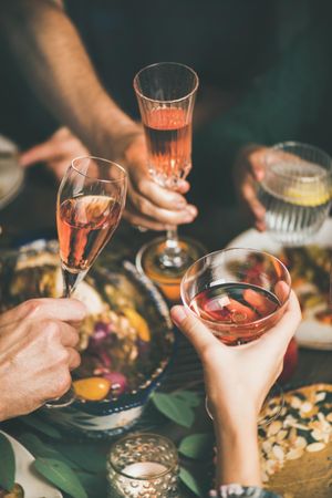 Group of people at festive fall dinner toasting with wine and water over pie, close up