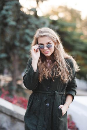 Teenage girl in dark coat wearing sunglasses and standing outdoor