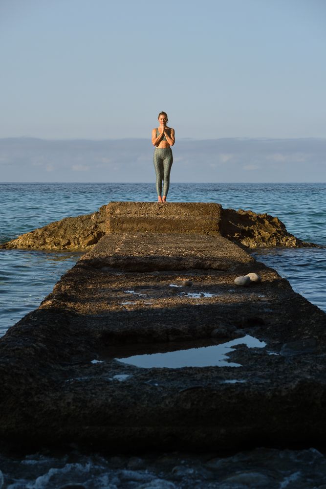 Slim woman standing on stone pier in sea