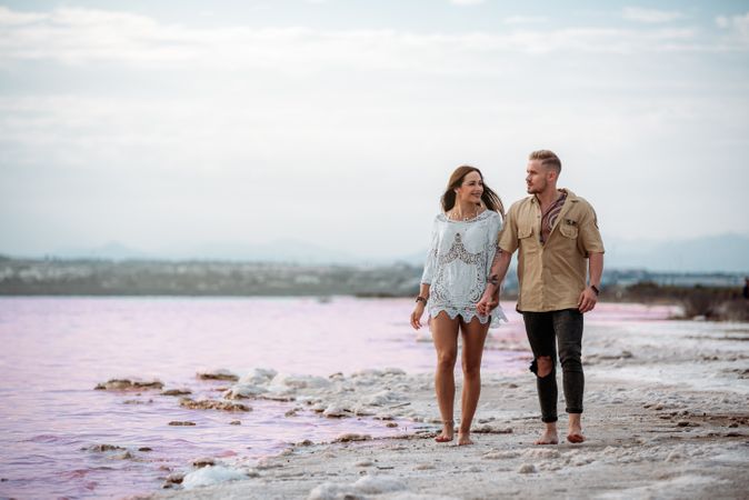 adorable couple walking on an amazing beach with pink water