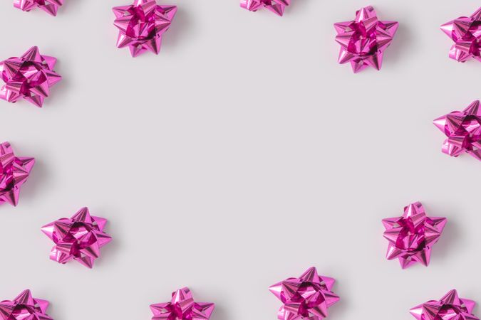 Pattern of plastic pink decorative gift bows bordering light background