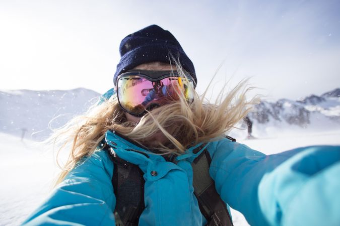Woman in winter gear taking selfie on cold day at a ski resort