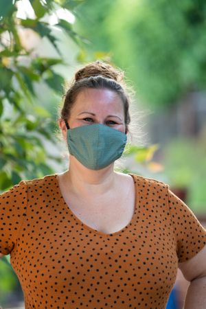 Close up portrait of woman in homemade coronavirus mask smiling and looking at camera