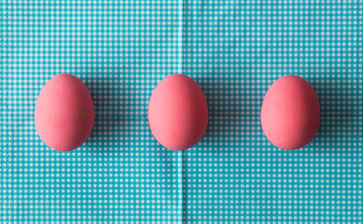 Row of three pink Easter eggs on blue background