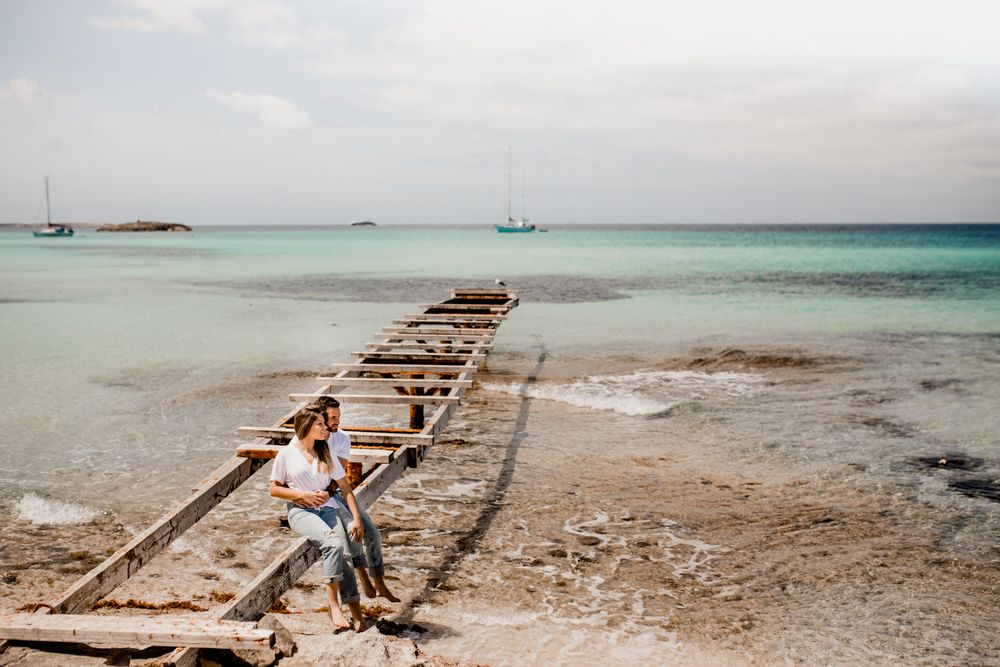 Glad lovers sitting on destroyed pier on seashore