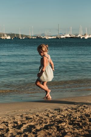 Blond girl walking towards the sea with ships