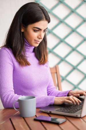 Female sitting on deck concentrating on computer, vertical