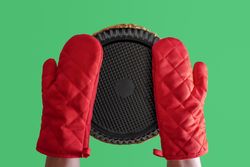 Bottom view of person wearing oven mitts and holding a pie dish