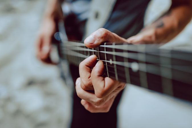 Man clamping strings on guitar neck
