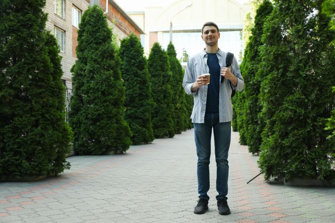 Young student hold backpack and cup of coffee. Study. University