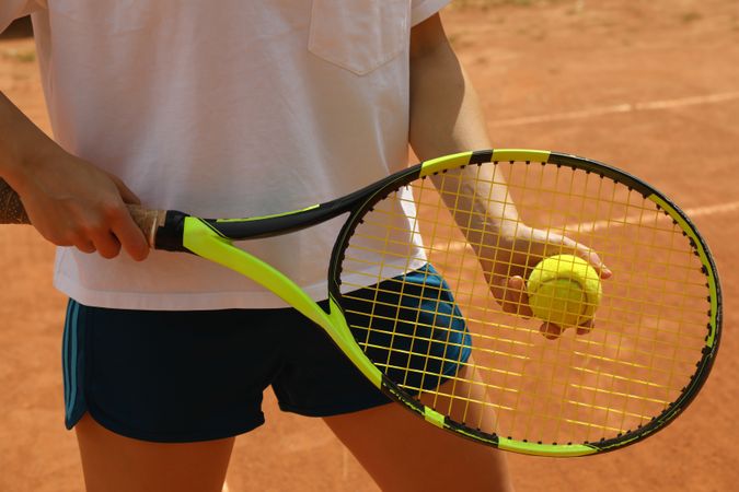 Woman hold racket and tennis ball on clay court