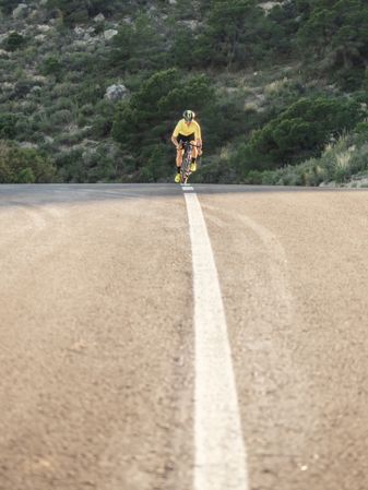 healthy man riding a bicycle on a mountain road in a sunny day