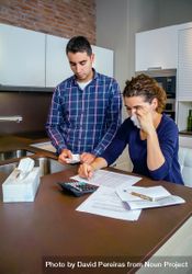 Sad couple going through their bills together in the kitchen with wife crying, vertical 4ONnZ5