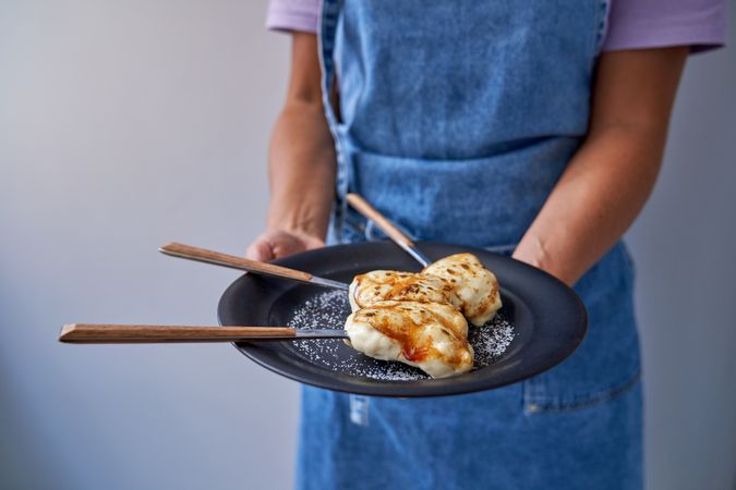 Crop person with frying roasted food in plate