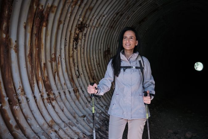Hispanic hiker with poles in dark tunnel