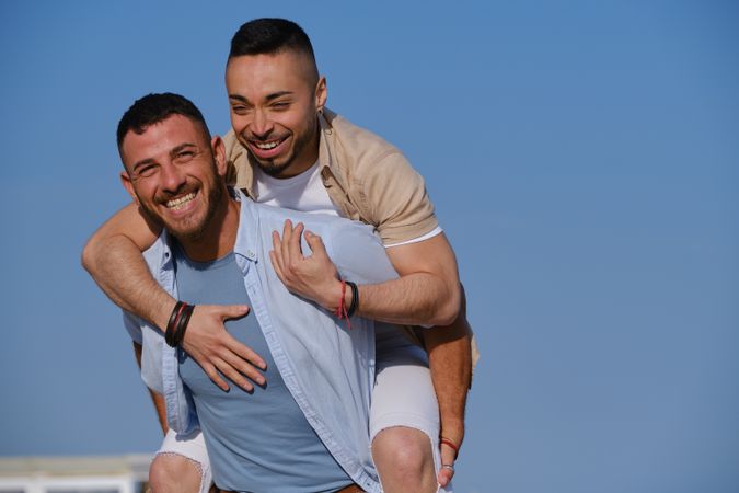 Happy gay couple playing piggyback