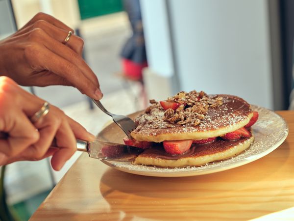Unrecognizable person cutting delicious pancakes