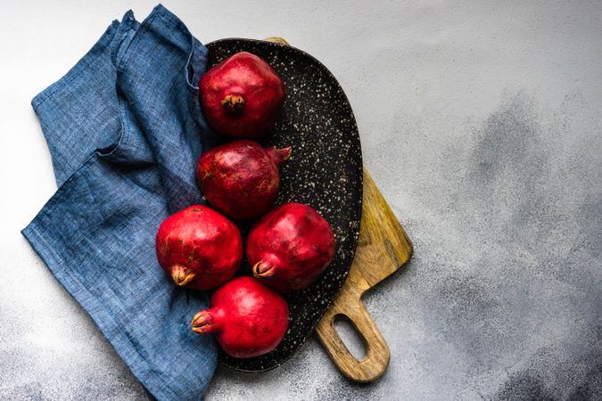 Whole pomegranates on board with napkin